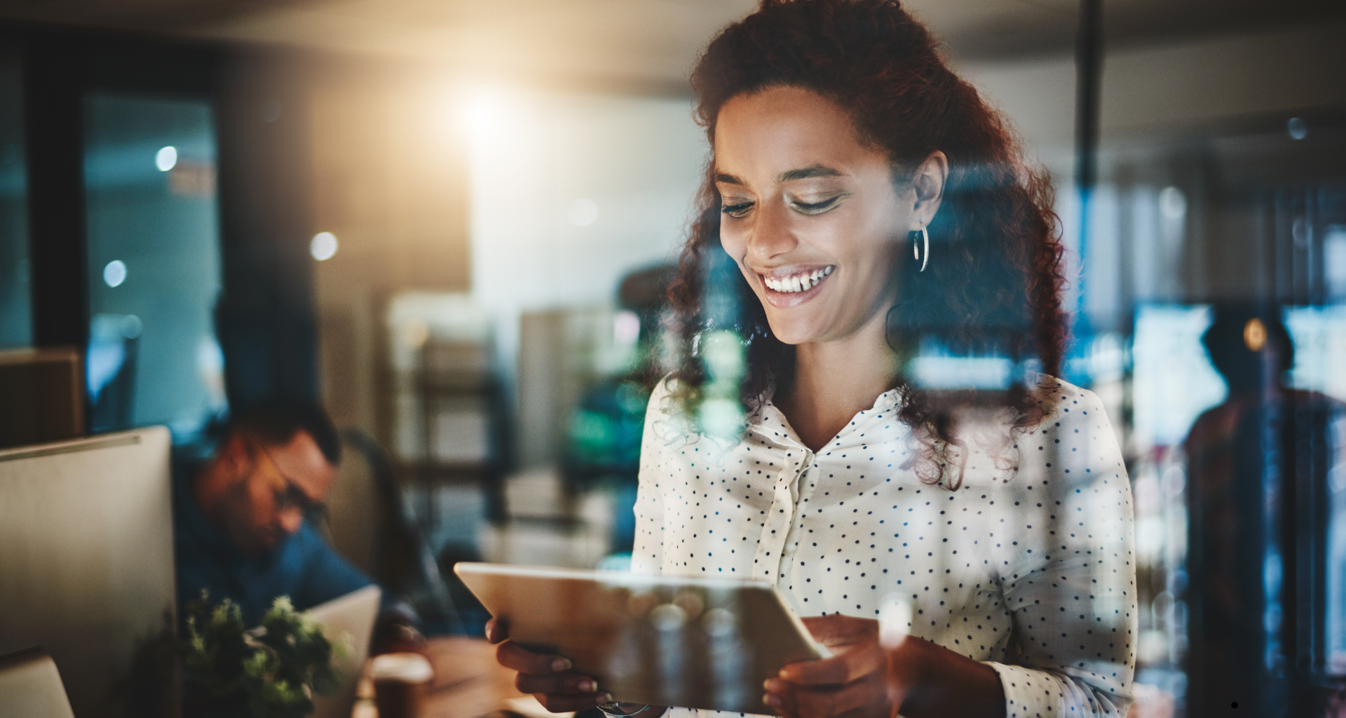 a woman smiling while holding a tablet